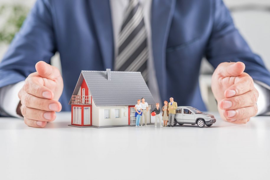 Insurance house, car and family health live concept. The insurance agent presents the toys that symbolize the coverage.